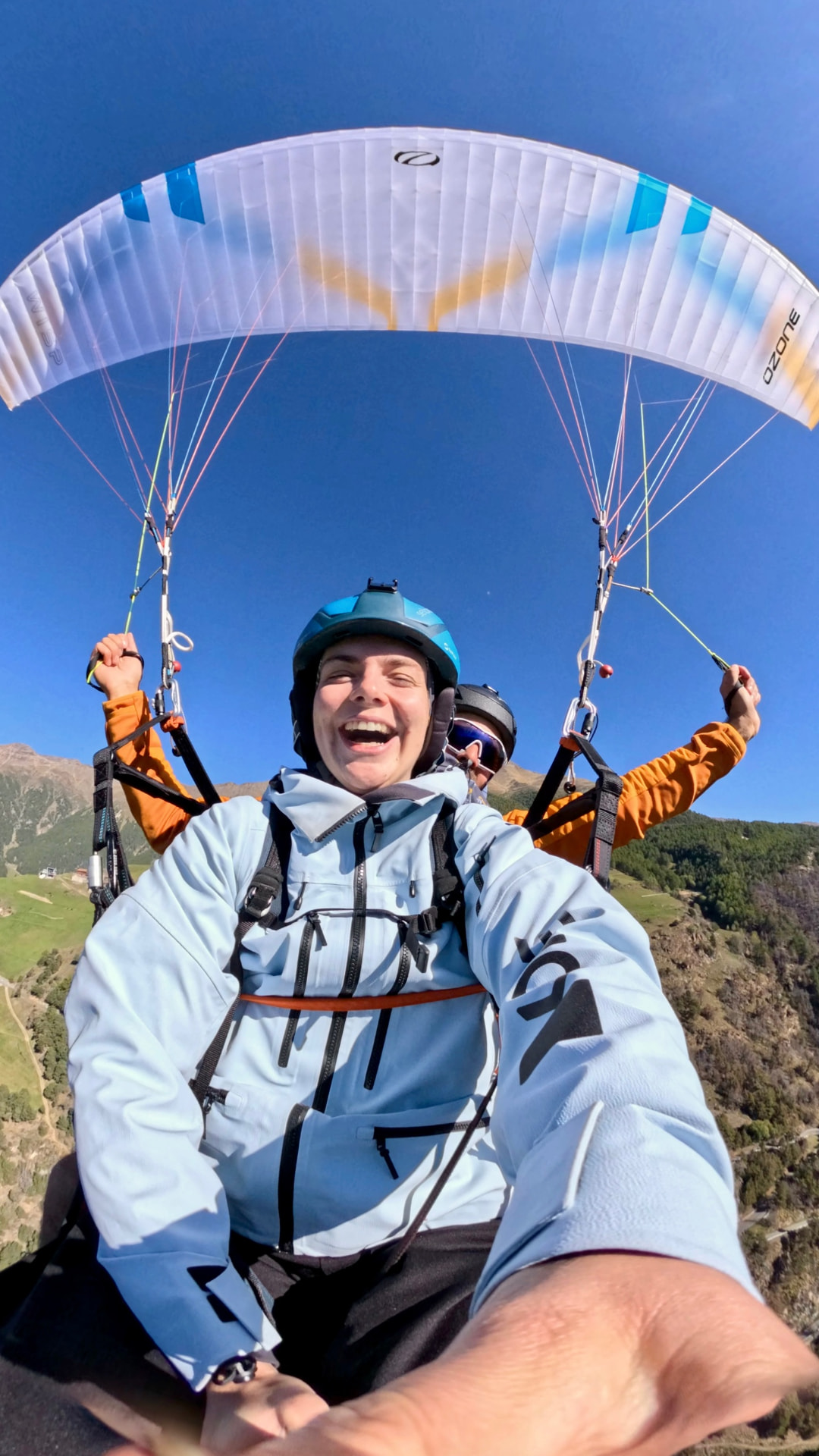 Lachender Passagier und Pilot im Tandemflug vor tiefblauem Himmel über dem Vinschgau